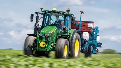 John Deere Traktor der Serie 6M auf dem grünen Feld