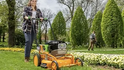 Frau beim Rasenmähen mit Handrasenmäher