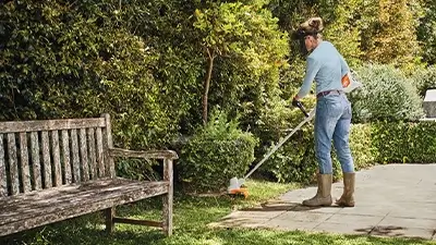 Frau bedient Garten-Gerät zum Schneiden des Rasens